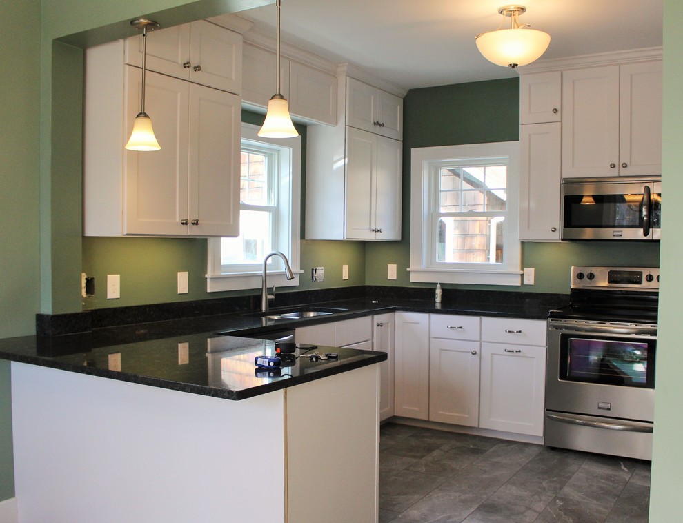 Inspiration for an arts and crafts eat-in kitchen in Portland Maine with an undermount sink, flat-panel cabinets, yellow cabinets, granite benchtops, stone slab splashback, stainless steel appliances, porcelain floors and a peninsula.