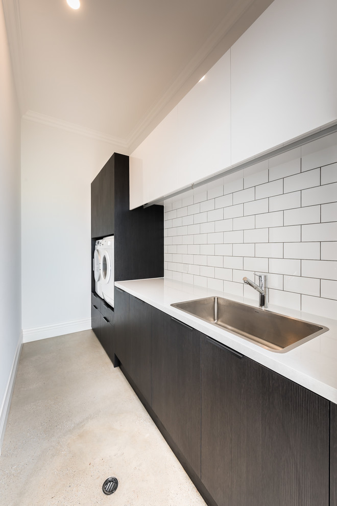 Design ideas for a large contemporary galley laundry room in Adelaide with an undermount sink, flat-panel cabinets, black cabinets, marble benchtops, white splashback, marble splashback, concrete floors and brown floor.