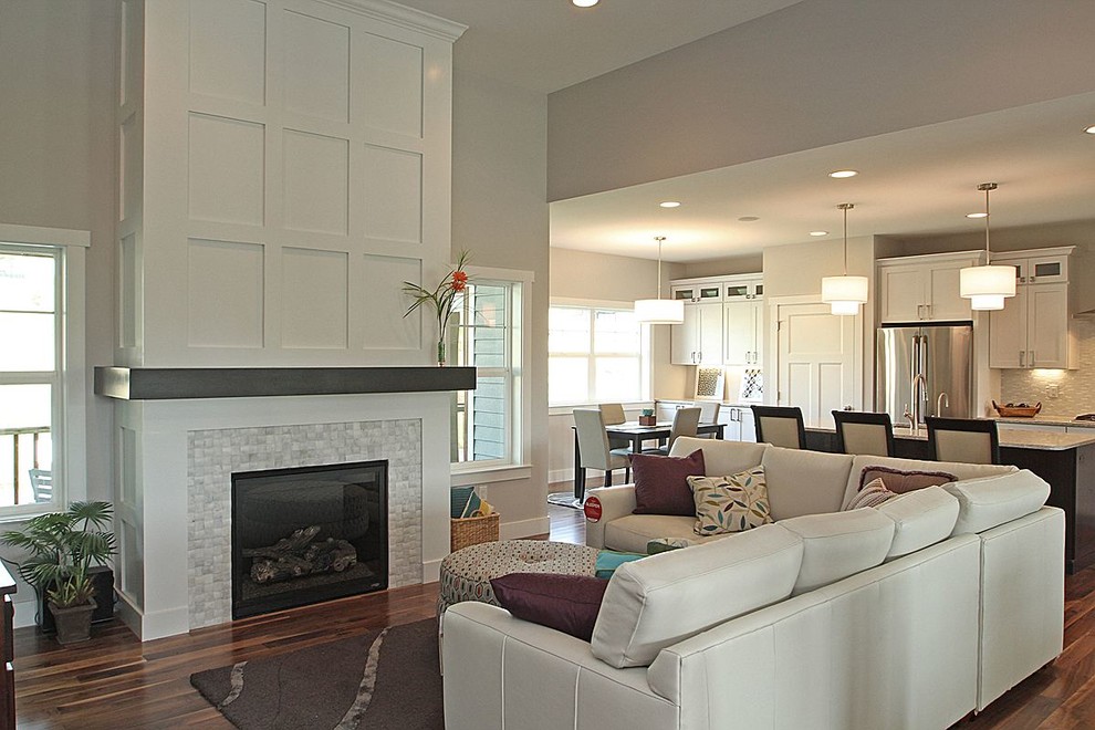 Photo of a mid-sized modern open concept living room in Cedar Rapids with grey walls, medium hardwood floors, a standard fireplace, a wood fireplace surround and brown floor.