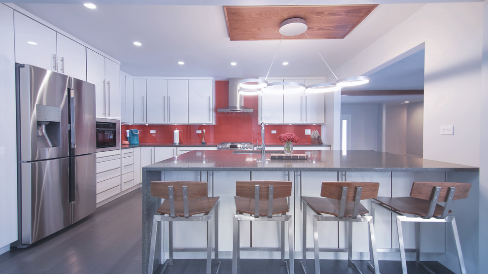 Inspiration for a mid-sized modern l-shaped eat-in kitchen in Chicago with an undermount sink, flat-panel cabinets, white cabinets, quartzite benchtops, red splashback, glass sheet splashback, stainless steel appliances, bamboo floors, with island and grey floor.