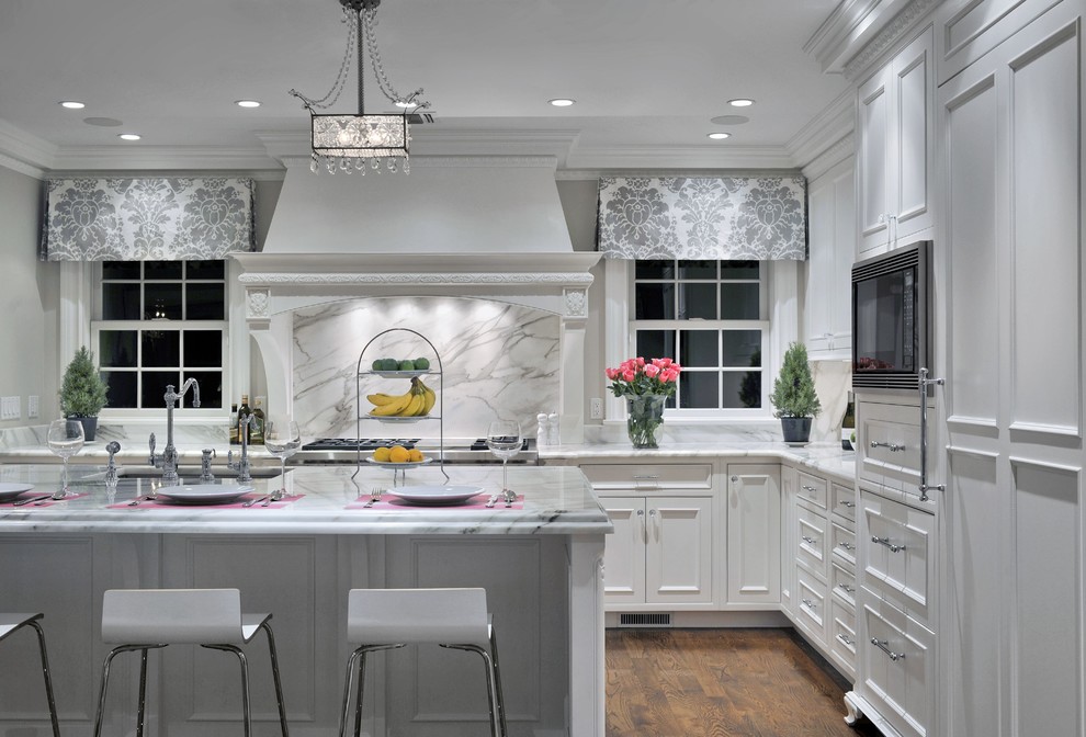 Large traditional l-shaped eat-in kitchen in New York with recessed-panel cabinets, white cabinets, marble benchtops, white splashback, stone slab splashback, stainless steel appliances, medium hardwood floors, with island and an undermount sink.