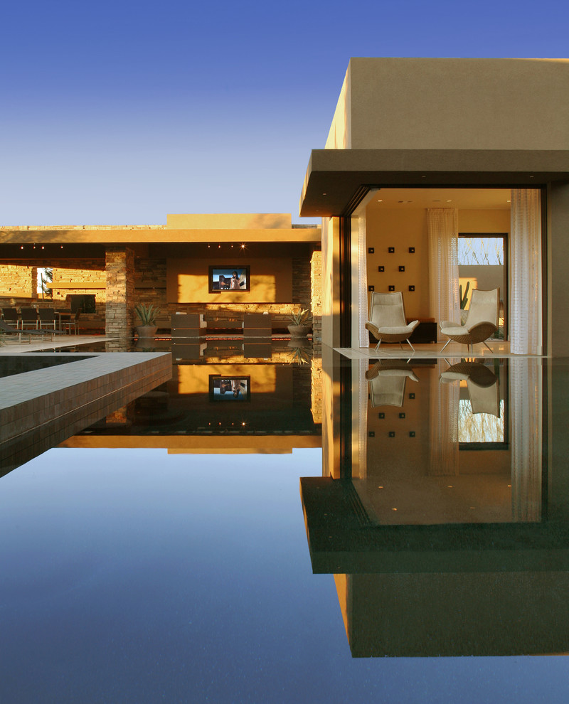 Expansive contemporary backyard custom-shaped infinity pool in Las Vegas with a hot tub.