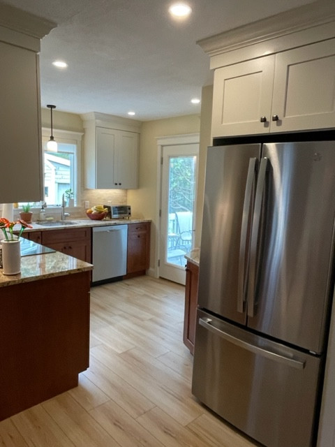 Mid-sized transitional l-shaped light wood floor and brown floor eat-in kitchen photo in Boston with an undermount sink, shaker cabinets, white cabinets, granite countertops, white backsplash, stainless steel appliances, no island, brown countertops and stone tile backsplash