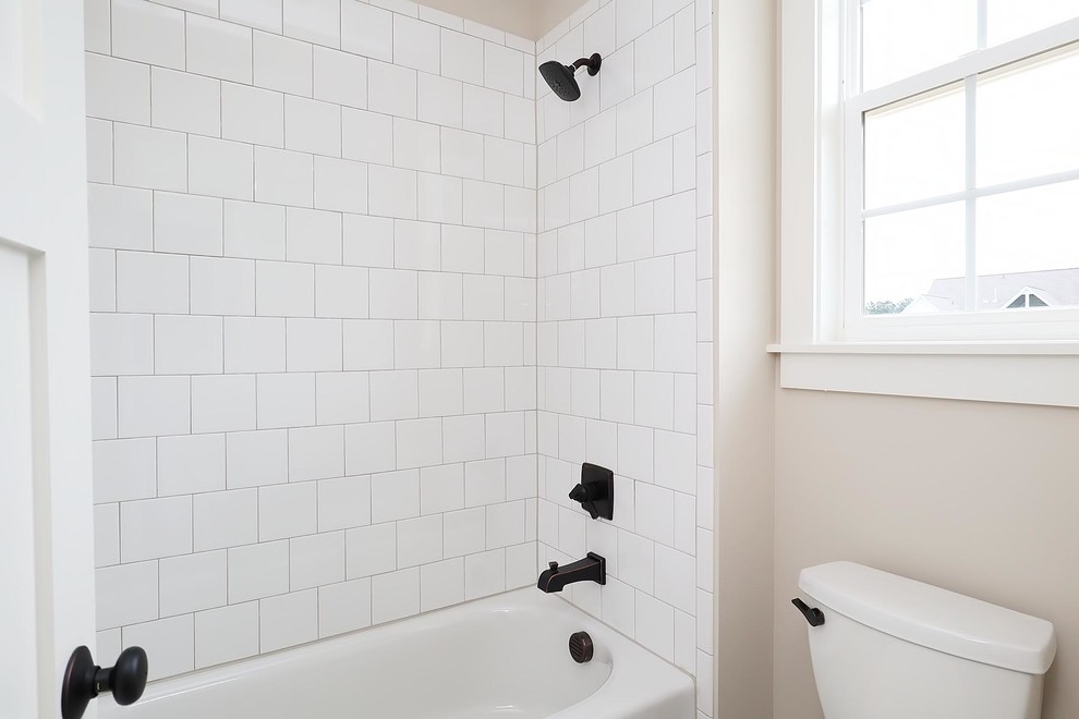 This is an example of a mid-sized traditional kids bathroom in Raleigh with recessed-panel cabinets, white cabinets, an alcove tub, a shower/bathtub combo, a one-piece toilet, white tile, ceramic tile, ceramic floors, an integrated sink, marble benchtops, a shower curtain, white benchtops, beige walls and white floor.