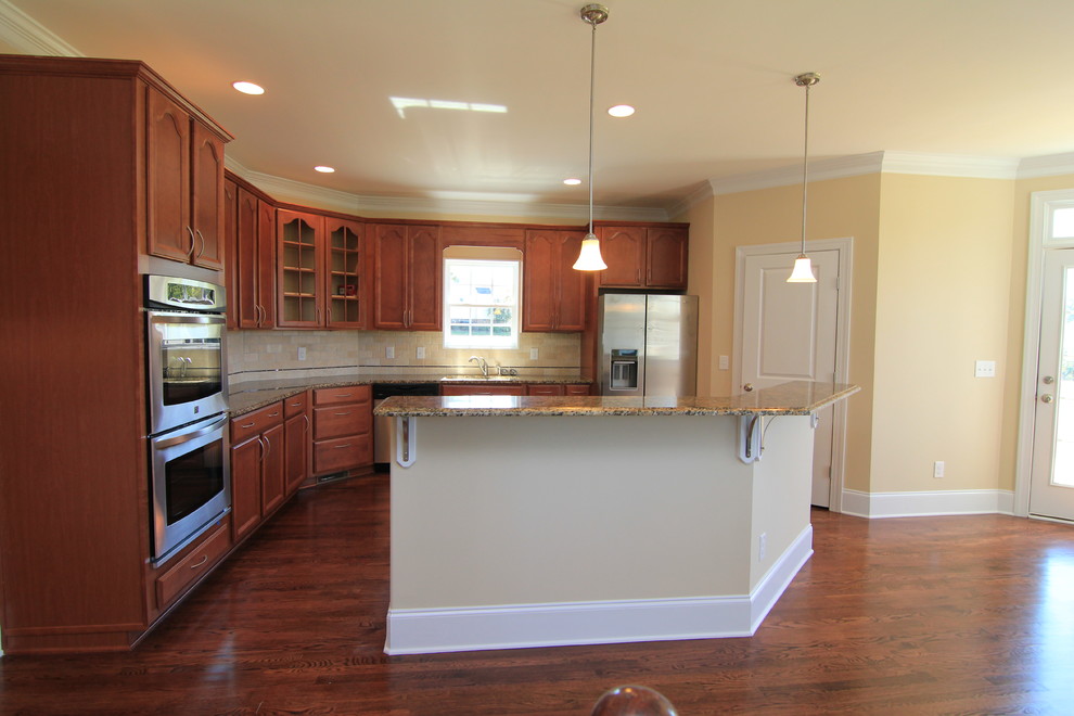 Inspiration for a large timeless u-shaped medium tone wood floor open concept kitchen remodel in Raleigh with an undermount sink, recessed-panel cabinets, medium tone wood cabinets, granite countertops, beige backsplash, ceramic backsplash, stainless steel appliances and an island