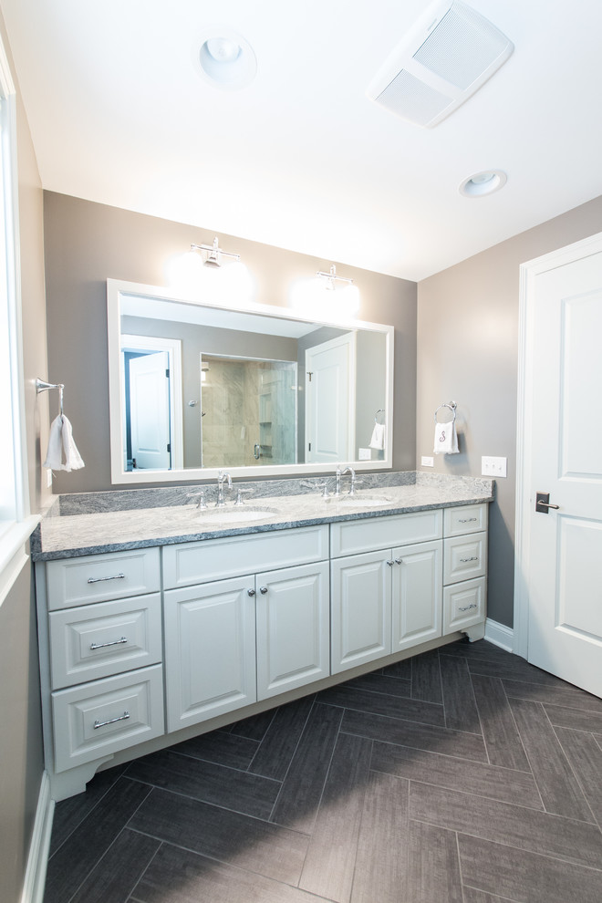 Inspiration for a mid-sized traditional master bathroom in Chicago with an undermount sink, raised-panel cabinets, white cabinets, granite benchtops, an alcove shower, a two-piece toilet, gray tile, stone tile, grey walls and porcelain floors.