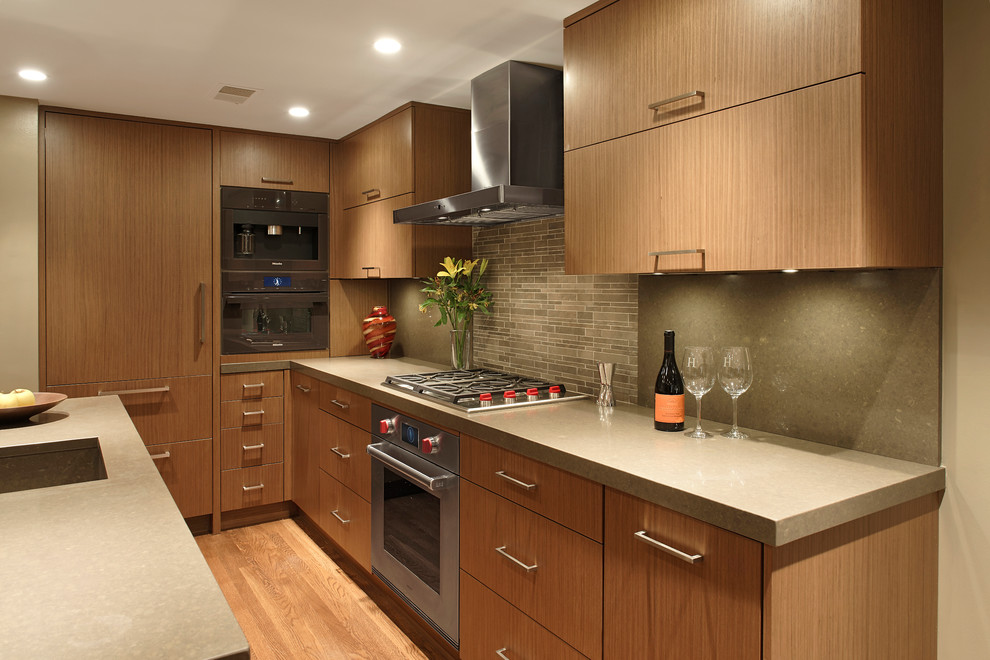 Photo of a mid-sized contemporary u-shaped eat-in kitchen in DC Metro with an integrated sink, flat-panel cabinets, medium wood cabinets, quartz benchtops, stone tile splashback, panelled appliances, with island, grey splashback and medium hardwood floors.