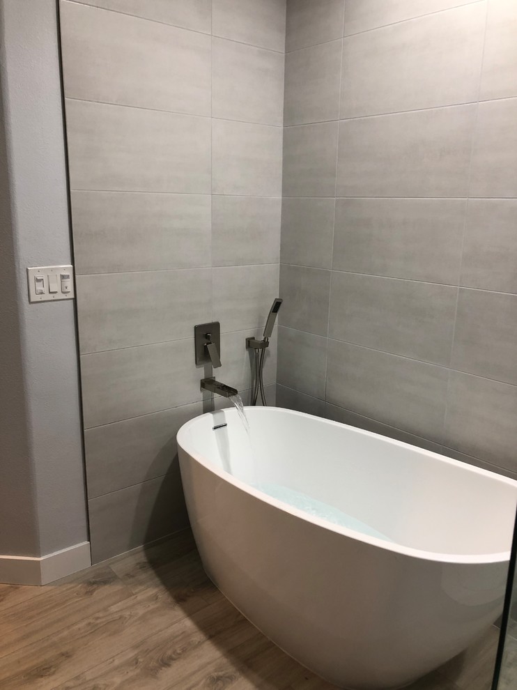 Inspiration for a large contemporary bathroom in Los Angeles with a corner tub, gray tile, cement tile, grey walls, plywood floors, beige floor, solid surface benchtops, a hinged shower door and white benchtops.