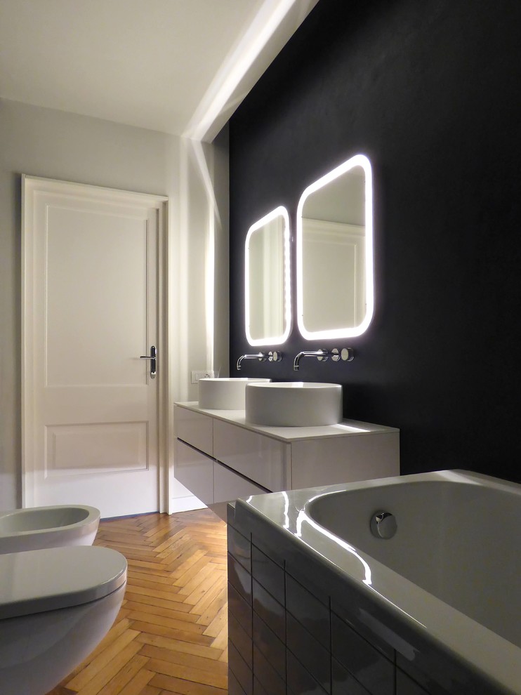 Design ideas for a mid-sized contemporary 3/4 bathroom in Other with flat-panel cabinets, white cabinets, a drop-in tub, a shower/bathtub combo, a two-piece toilet, blue walls, light hardwood floors, a vessel sink and solid surface benchtops.