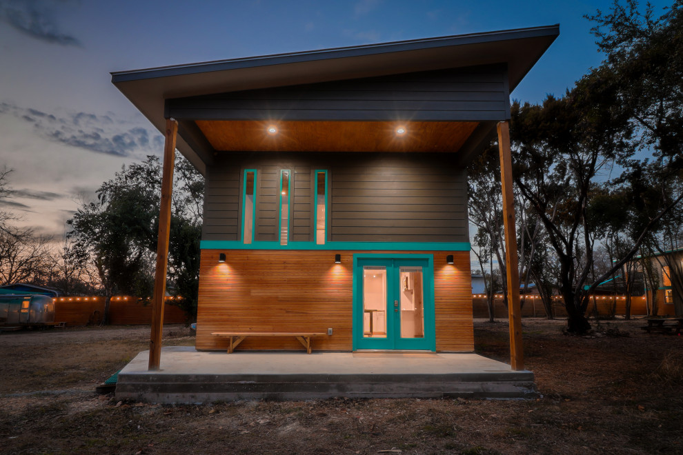 Пример оригинального дизайна: маленький, двухэтажный, синий мини дом в стиле фьюжн с комбинированной облицовкой, односкатной крышей, металлической крышей, серой крышей и отделкой доской с нащельником для на участке и в саду