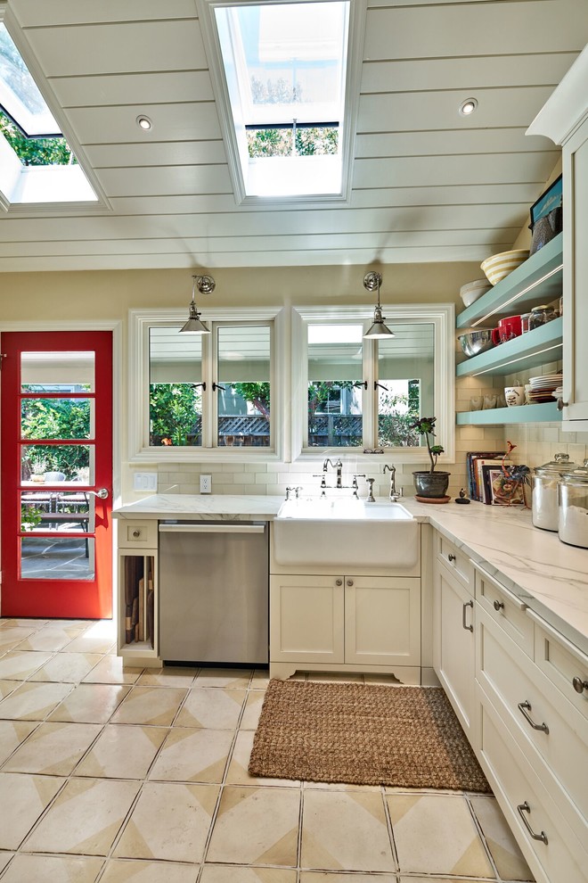 Mid-sized country l-shaped eat-in kitchen in San Francisco with a farmhouse sink, shaker cabinets, white cabinets, marble benchtops, white splashback, glass tile splashback, stainless steel appliances, ceramic floors and a peninsula.