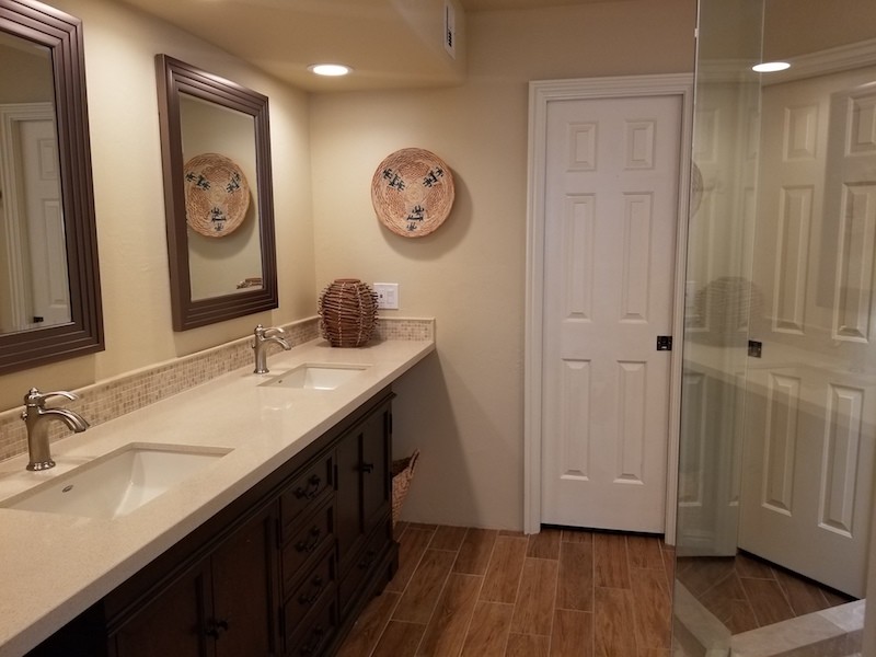 This is an example of a mid-sized traditional 3/4 bathroom in Phoenix with recessed-panel cabinets, dark wood cabinets, a corner shower, beige walls, medium hardwood floors, an undermount sink, engineered quartz benchtops, brown floor, a hinged shower door and beige benchtops.
