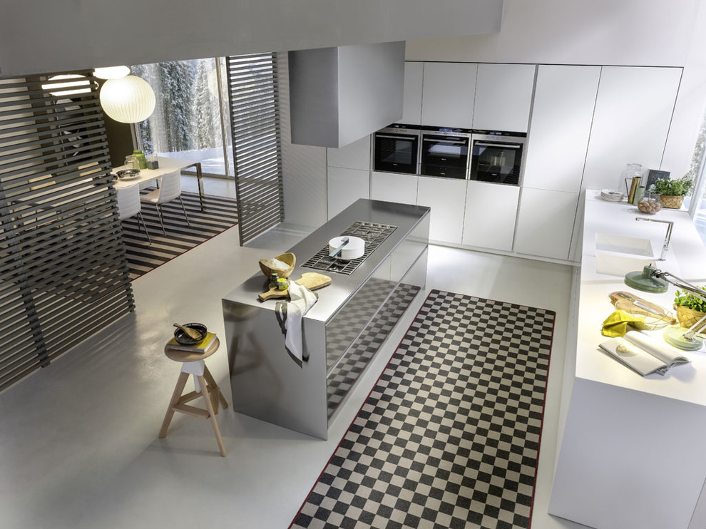 Large contemporary l-shaped eat-in kitchen in Turin with a double-bowl sink, glass-front cabinets, white cabinets, solid surface benchtops, white splashback, slate splashback, stainless steel appliances, concrete floors and with island.