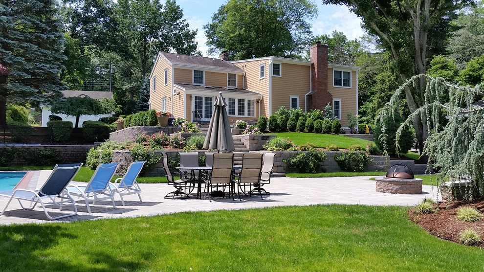 Photo of a large traditional backyard custom-shaped lap pool in New York with natural stone pavers.