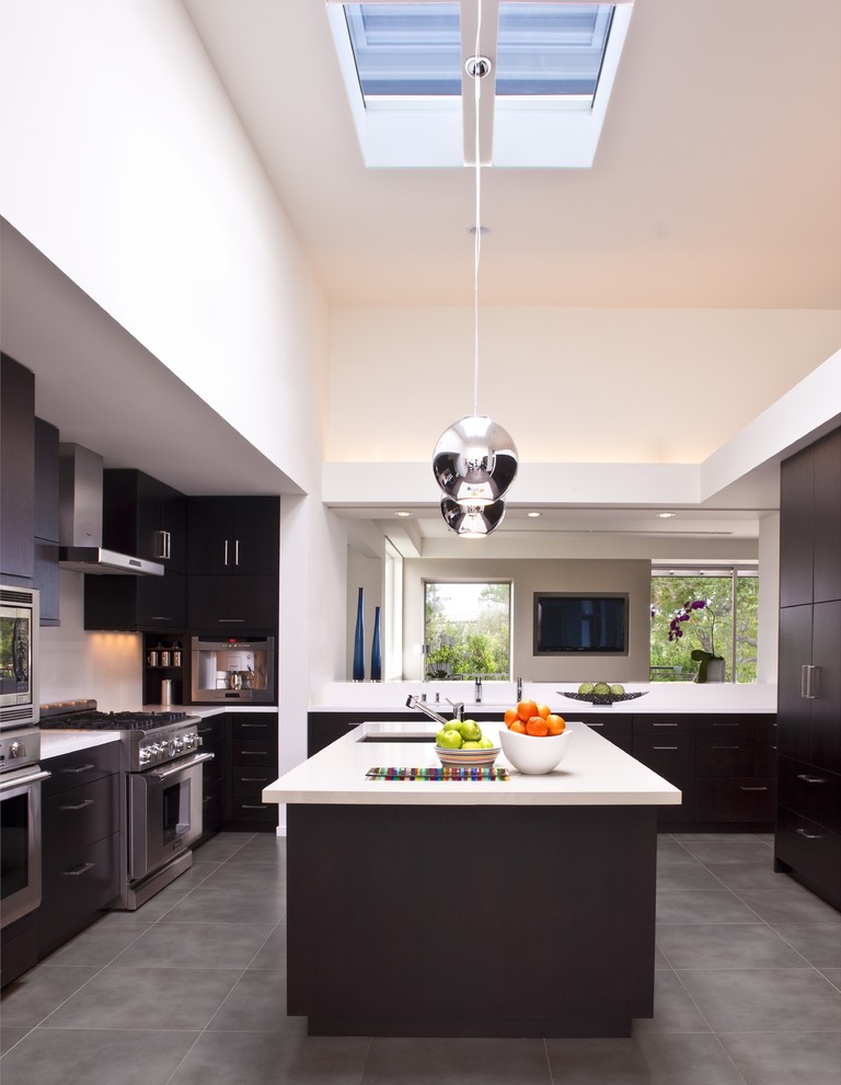 This is an example of a contemporary u-shaped open plan kitchen in Los Angeles with an undermount sink, flat-panel cabinets, dark wood cabinets, quartz benchtops, white splashback, stone slab splashback, stainless steel appliances and grey floor.