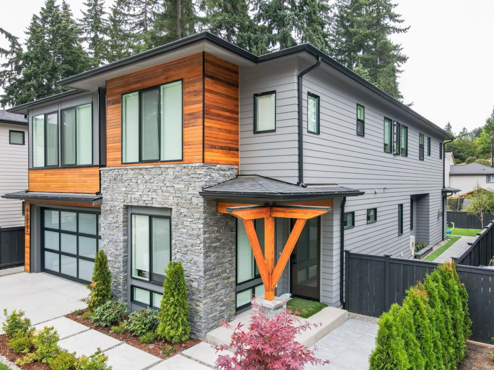 Photo of a large modern two-storey grey townhouse exterior in Seattle with mixed siding, a flat roof, a metal roof, a black roof and board and batten siding.