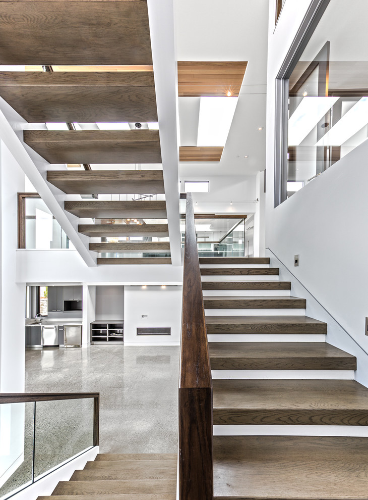 Large contemporary wood u-shaped staircase in Seattle with open risers and glass railing.
