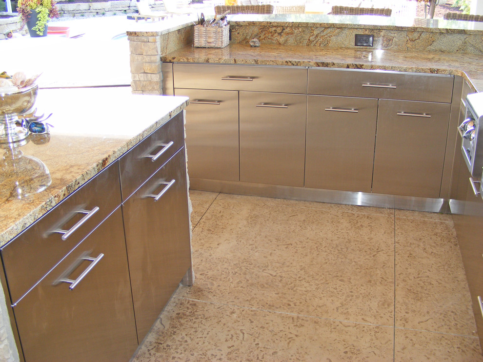 Photo of a mid-sized beach style u-shaped eat-in kitchen in Other with a single-bowl sink, flat-panel cabinets, stainless steel cabinets, granite benchtops, multi-coloured splashback, stone slab splashback, stainless steel appliances, concrete floors, with island, beige floor and beige benchtop.