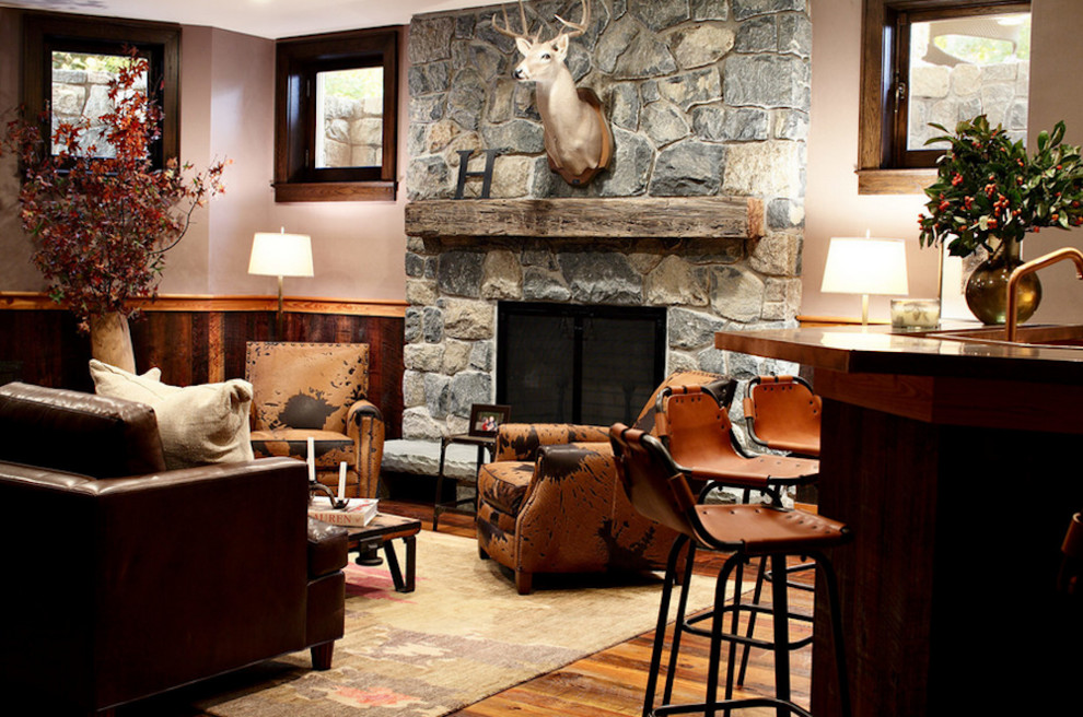 This is an example of a mid-sized country enclosed living room in New York with medium hardwood floors, a standard fireplace, a stone fireplace surround and brown walls.