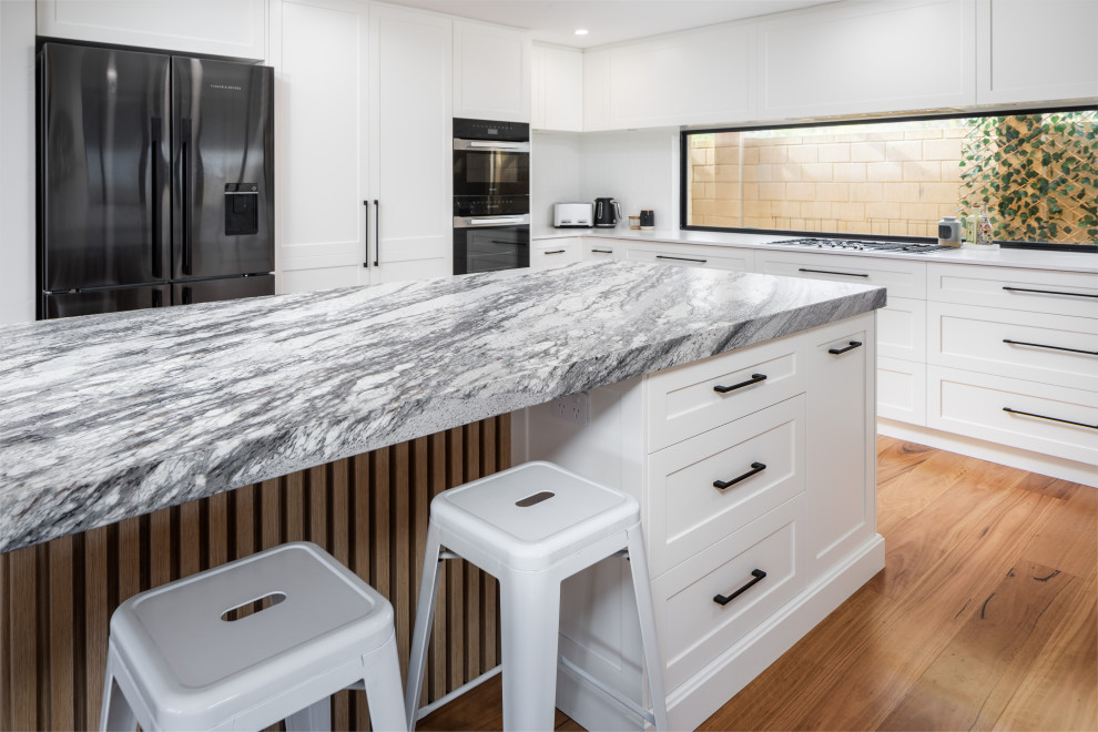 Kitchen - traditional medium tone wood floor kitchen idea in Perth with an undermount sink, shaker cabinets, white cabinets, granite countertops, white backsplash, subway tile backsplash, black appliances, an island and gray countertops