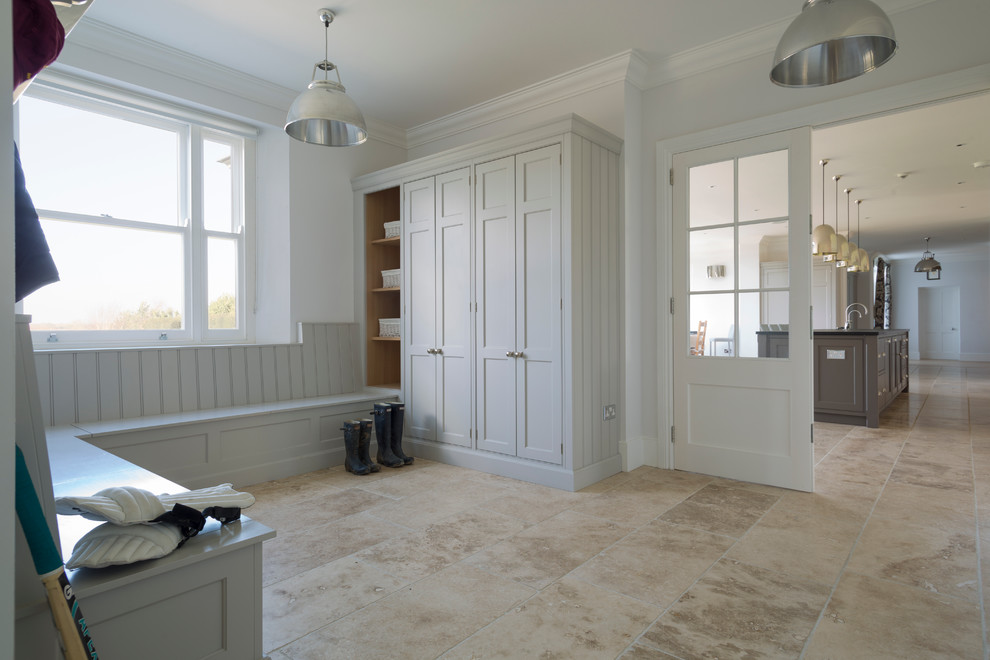 Design ideas for a mid-sized transitional entryway in Essex with white walls and travertine floors.