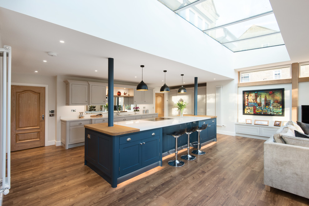 Expansive transitional open plan kitchen in Other with an undermount sink, shaker cabinets, grey cabinets, dark hardwood floors, with island, brown floor and white benchtop.