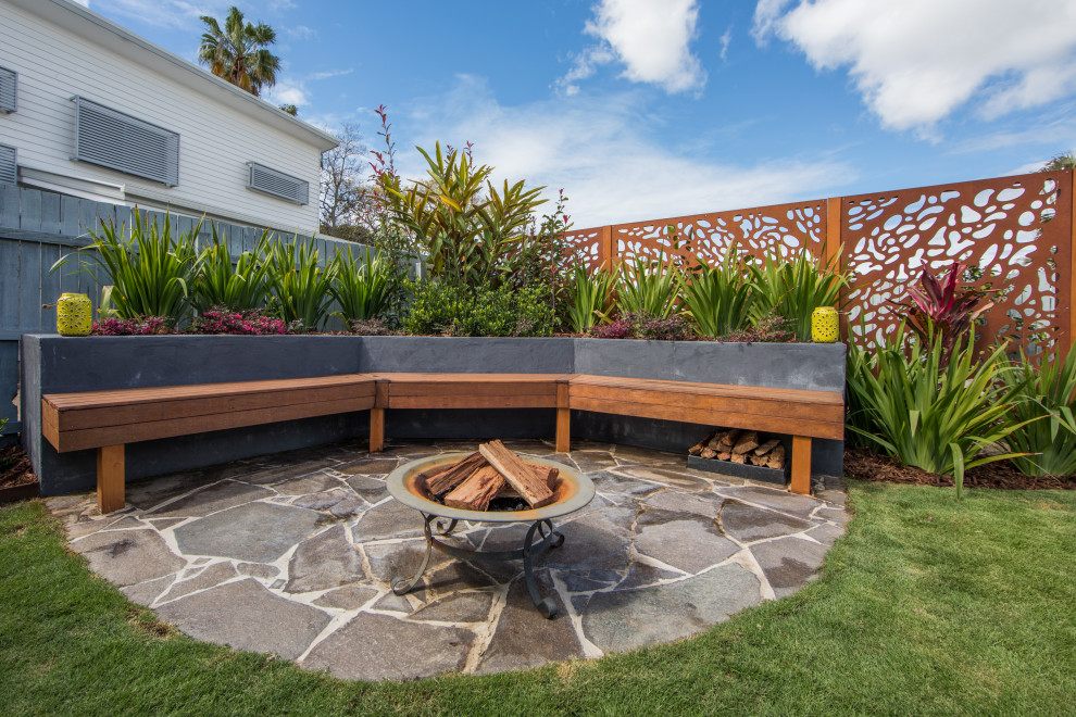 This is an example of a mid-sized modern backyard patio in Brisbane with natural stone pavers.