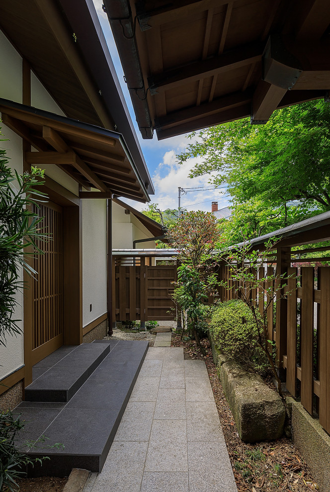Diseño de terraza asiática grande en patio delantero y anexo de casas con zócalos y adoquines de piedra natural