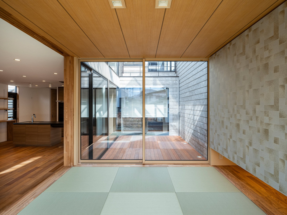 Modelo de salón abierto y beige de tamaño medio sin chimenea con paredes blancas, tatami, suelo verde, madera y papel pintado