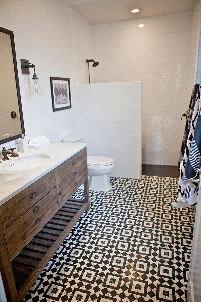 This is an example of a mid-sized transitional bathroom in San Diego with medium wood cabinets, an alcove shower, a one-piece toilet, black and white tile, cement tile, white walls, ceramic floors, an undermount sink, marble benchtops and furniture-like cabinets.