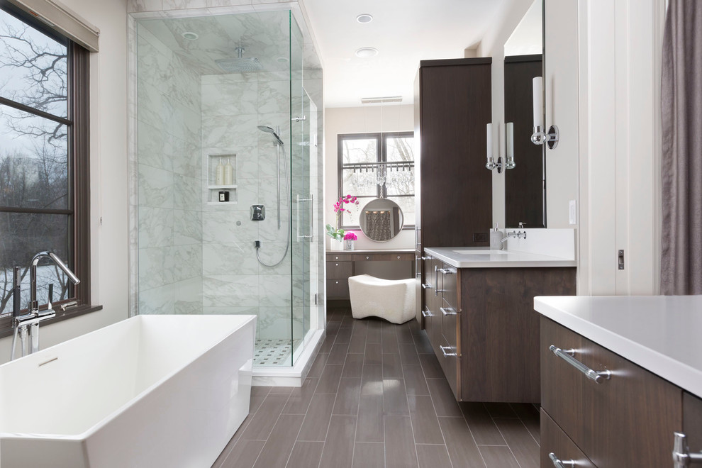 This is an example of an expansive contemporary master bathroom in Milwaukee with a hinged shower door, flat-panel cabinets, brown cabinets, a freestanding tub, a double shower, an integrated sink, laminate benchtops, white benchtops, white walls and brown floor.