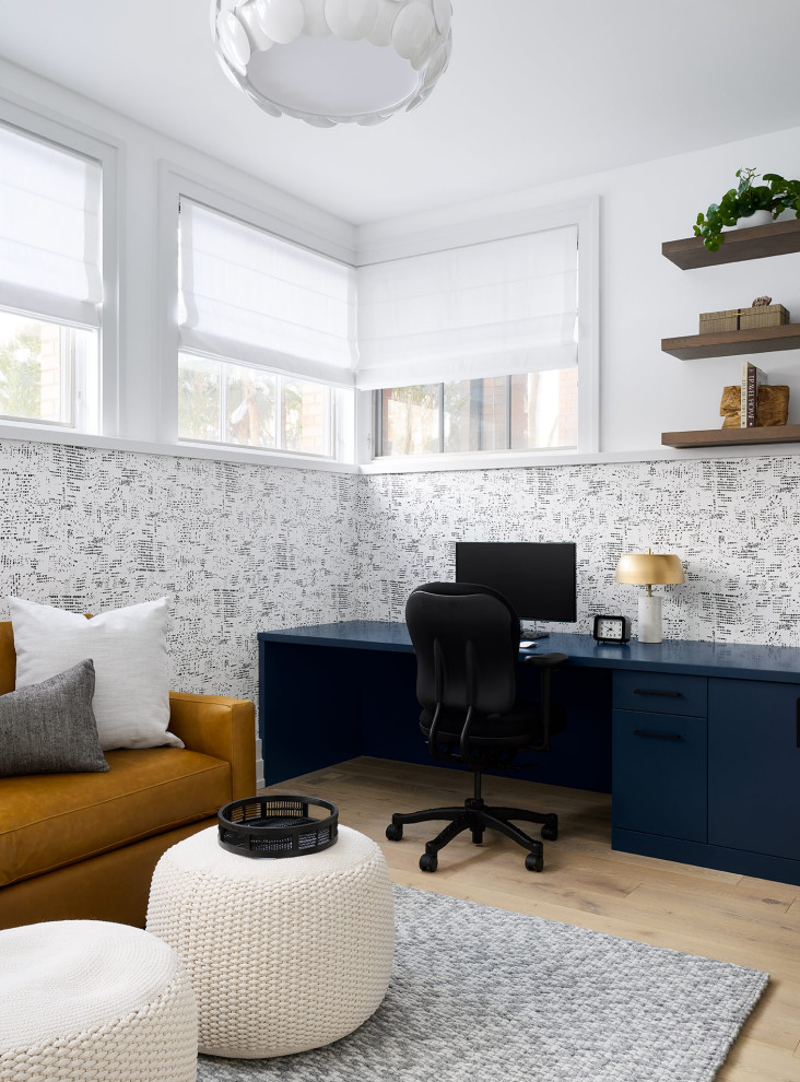 На фото: рабочее место в стиле модернизм с белыми стенами, светлым паркетным полом, встроенным рабочим столом и обоями на стенах