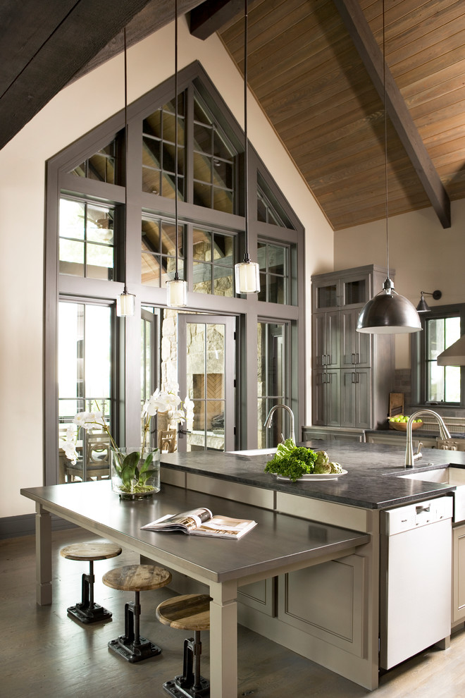 Photo of a large contemporary u-shaped eat-in kitchen in Other with a farmhouse sink, beaded inset cabinets, beige cabinets, soapstone benchtops, black splashback, subway tile splashback, stainless steel appliances, medium hardwood floors, with island, beige floor and black benchtop.