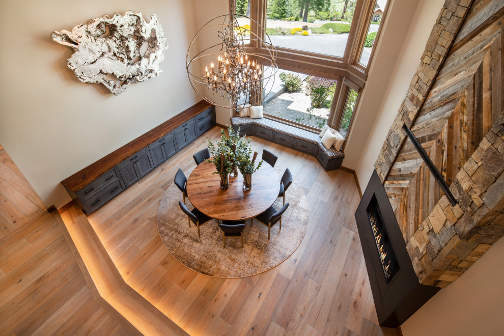 Idée de décoration pour une grande salle à manger ouverte sur le salon chalet avec un mur gris, un sol en bois brun, une cheminée standard, un manteau de cheminée en métal, un sol marron et un plafond voûté.