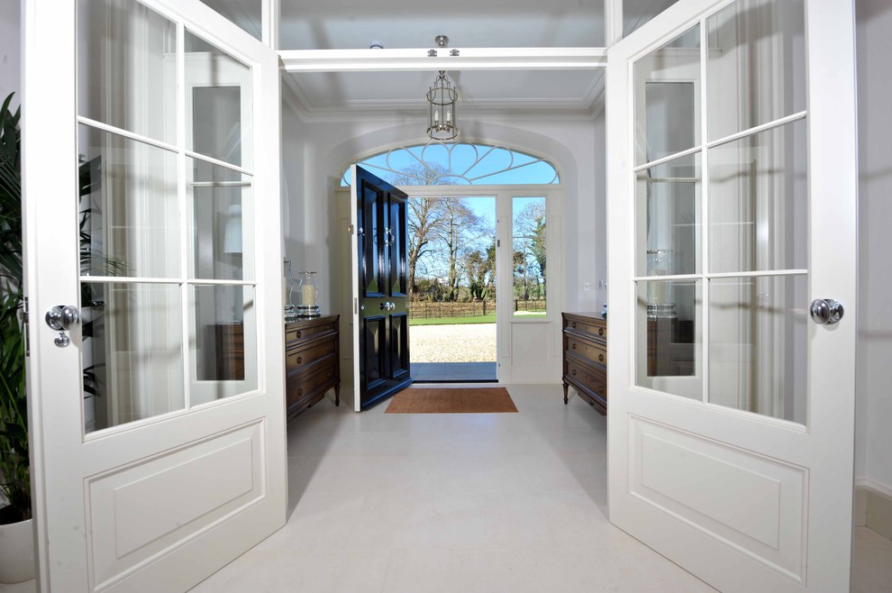 This is an example of a large traditional foyer in Hertfordshire with white walls, porcelain floors, a single front door, a black front door and white floor.