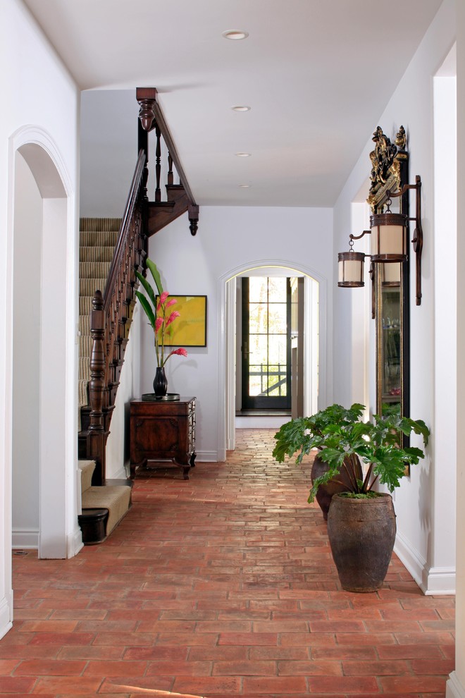 This is an example of a large mediterranean entry hall in Chicago with white walls and brick floors.
