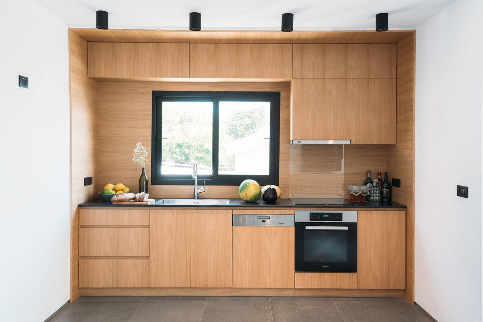 Small modern single-wall separate kitchen in Other with a single-bowl sink, flat-panel cabinets, light wood cabinets, granite benchtops, stainless steel appliances, ceramic floors, no island, grey floor, black benchtop, beige splashback and timber splashback.