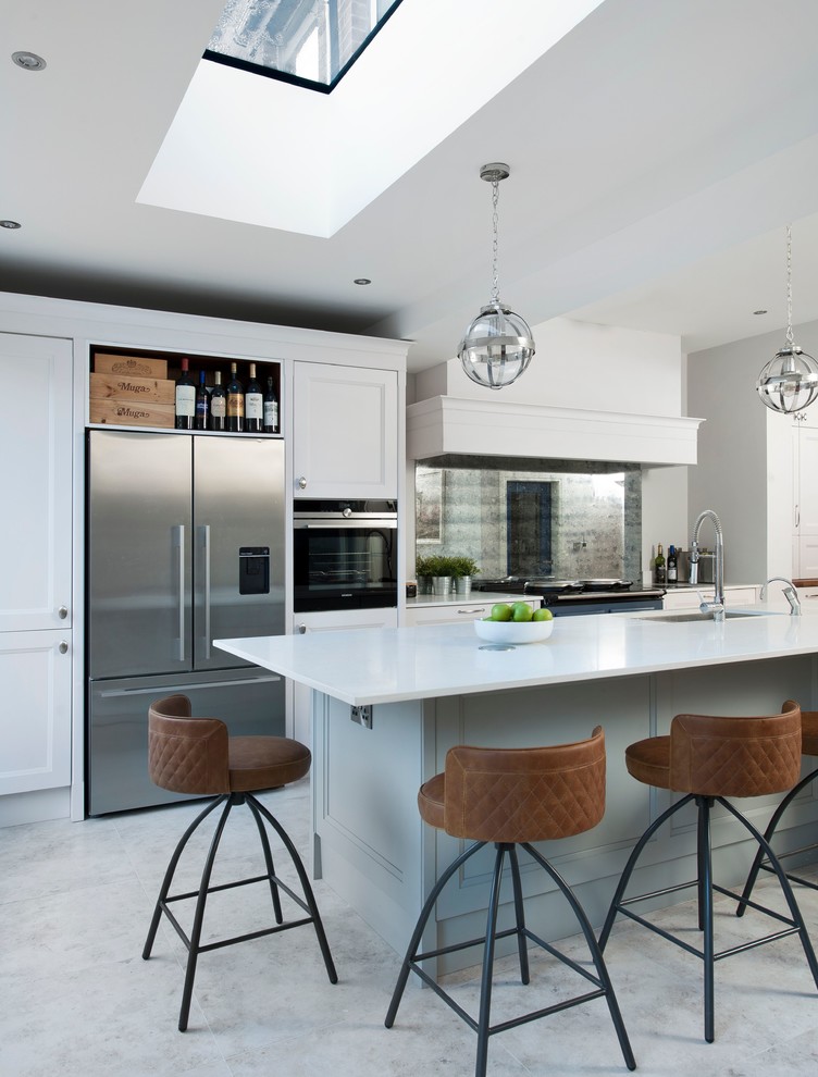 Photo of a mid-sized transitional eat-in kitchen in Belfast with a double-bowl sink, recessed-panel cabinets, white cabinets, mirror splashback, coloured appliances, with island and white floor.