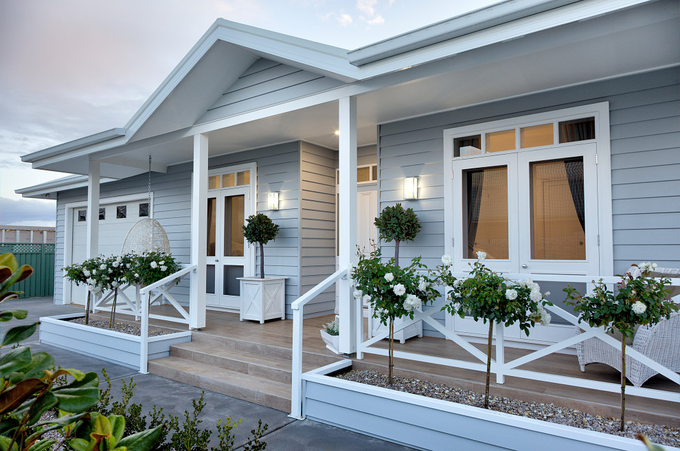 Idées déco pour un porche d'entrée de maison bord de mer avec une terrasse en bois et une extension de toiture.