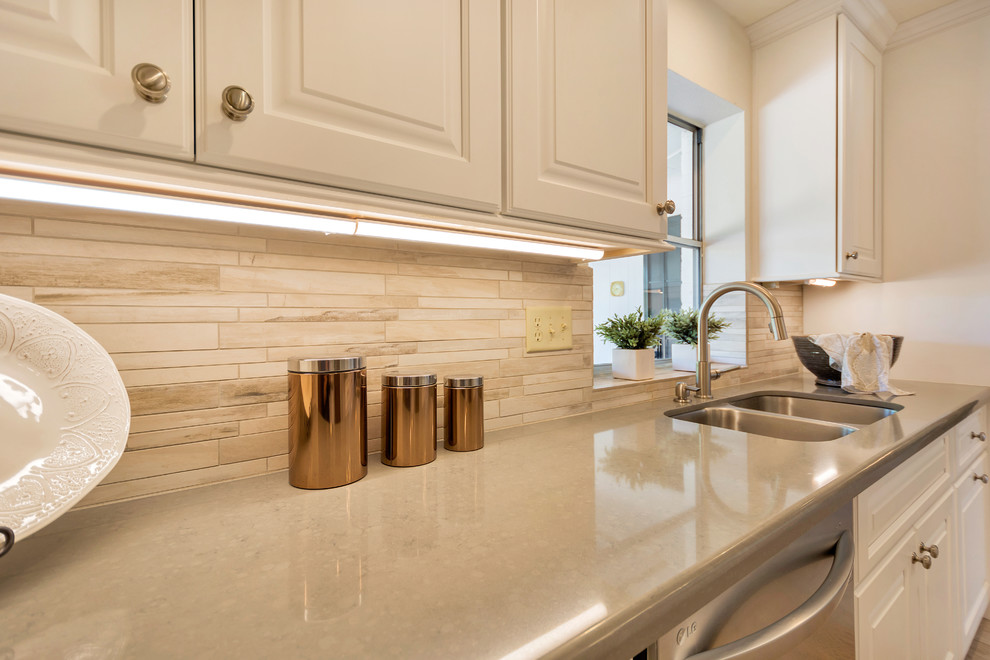 Example of a large transitional l-shaped porcelain tile open concept kitchen design in Phoenix with an undermount sink, raised-panel cabinets, white cabinets, quartz countertops, beige backsplash, porcelain backsplash, stainless steel appliances and an island