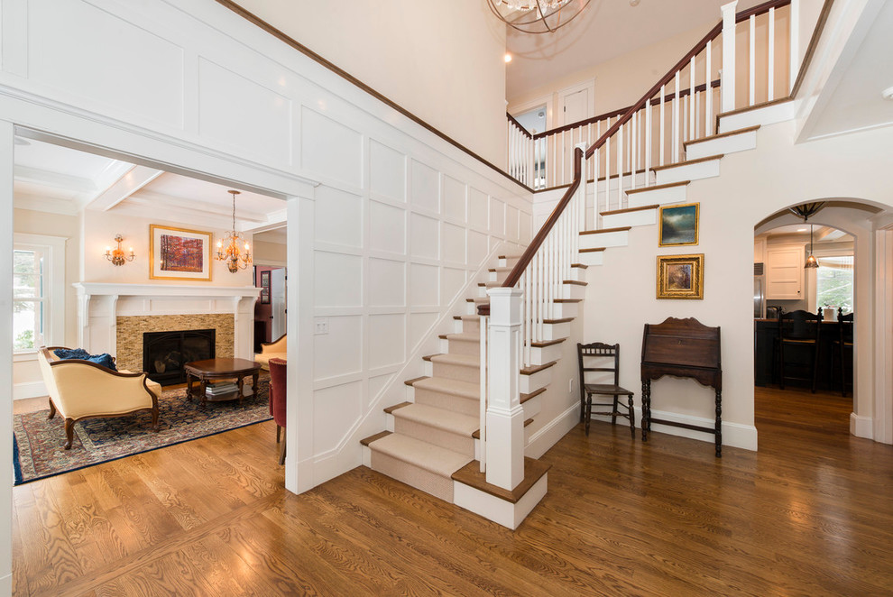 Large traditional wood l-shaped staircase in Boston with painted wood risers.