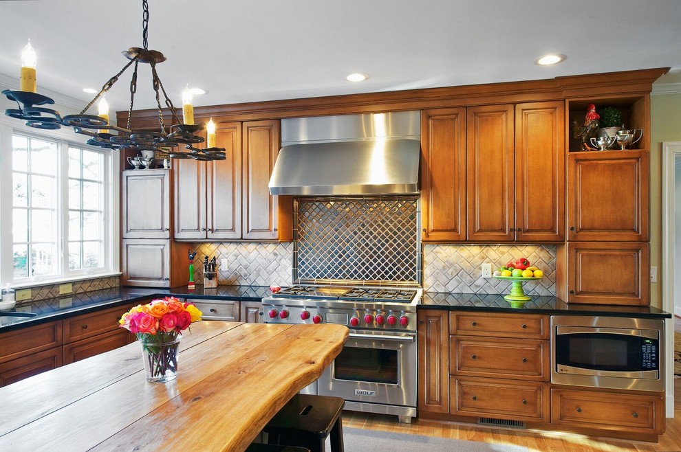 Inspiration for a mid-sized rustic l-shaped medium tone wood floor and brown floor open concept kitchen remodel in Orange County with an undermount sink, raised-panel cabinets, medium tone wood cabinets, granite countertops, beige backsplash, ceramic backsplash, stainless steel appliances and an island