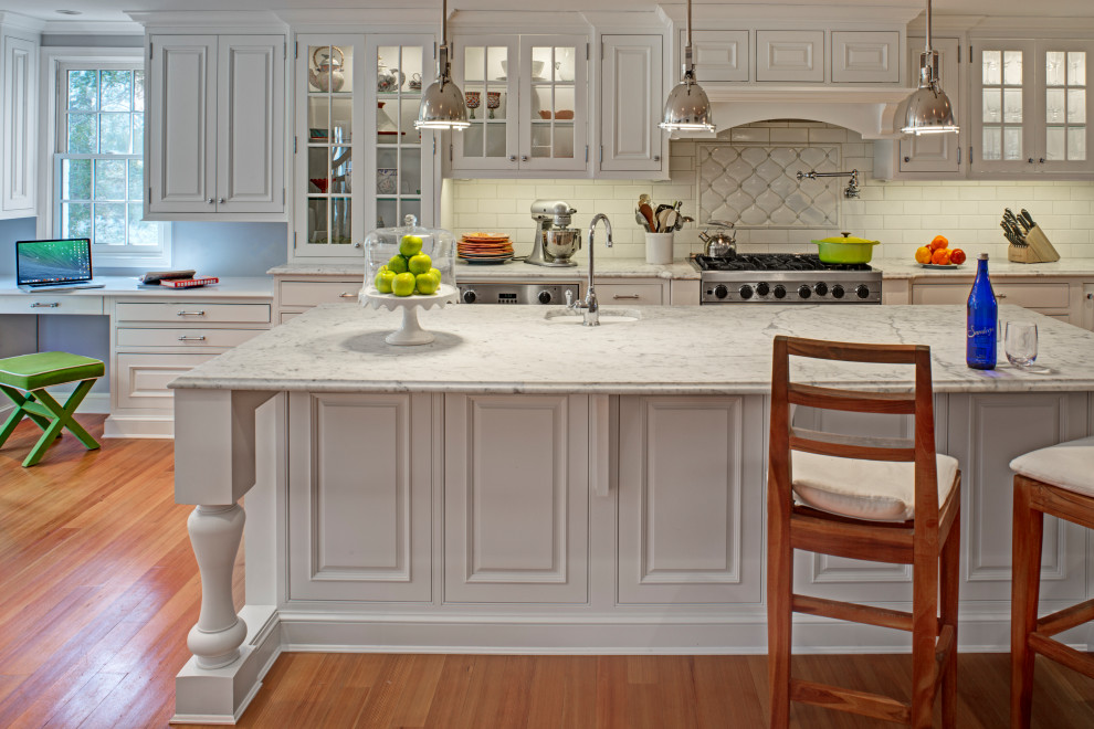 Transitional medium tone wood floor and brown floor eat-in kitchen photo in Baltimore with white cabinets, marble countertops, white backsplash, stainless steel appliances, an island and white countertops