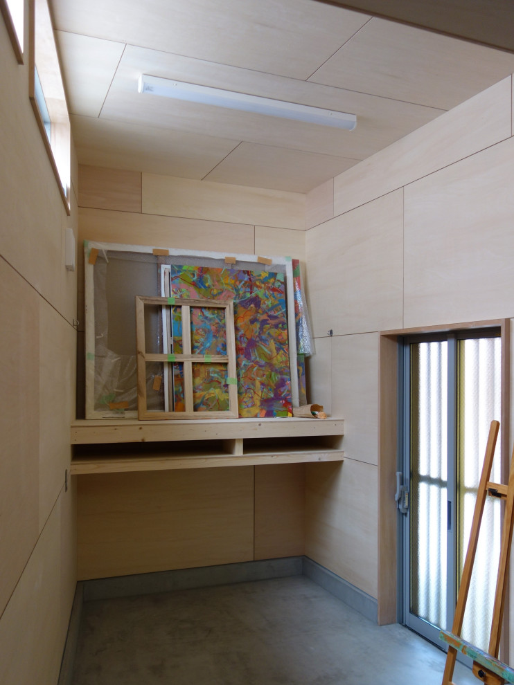 На фото: домашняя мастерская среднего размера в современном стиле с бежевыми стенами, бетонным полом, встроенным рабочим столом, серым полом, деревянным потолком и деревянными стенами без камина