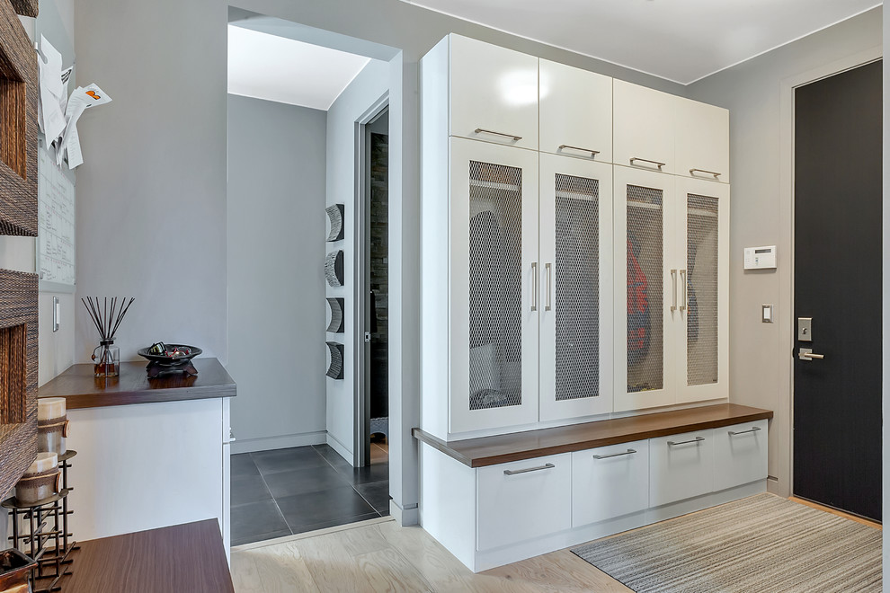 Photo of a large contemporary mudroom in Minneapolis with grey walls, light hardwood floors, a single front door and a black front door.