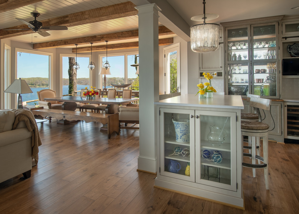 Inspiration for a large coastal u-shaped medium tone wood floor and brown floor open concept kitchen remodel with a farmhouse sink, flat-panel cabinets, gray cabinets, quartz countertops, white backsplash, ceramic backsplash, stainless steel appliances, two islands and white countertops