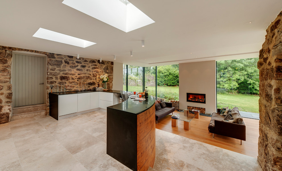 This is an example of a large country open plan kitchen in Devon with an undermount sink, flat-panel cabinets, white cabinets, a peninsula and limestone floors.