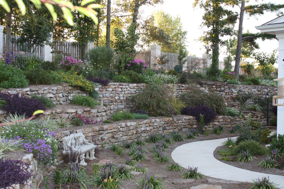 This is an example of a mid-sized traditional backyard full sun garden for summer in Other with a retaining wall and brick pavers.