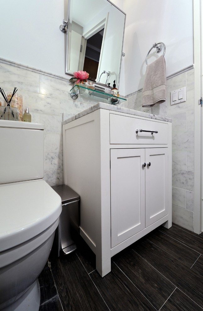 Inspiration for a small contemporary bathroom in New York with an integrated sink, raised-panel cabinets, white cabinets, marble benchtops, a two-piece toilet, white tile, grey walls and dark hardwood floors.