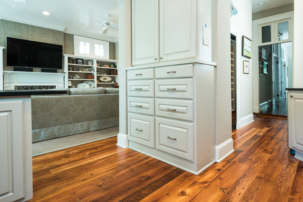 Enclosed kitchen - mid-sized transitional u-shaped medium tone wood floor and brown floor enclosed kitchen idea in Charleston with a farmhouse sink, raised-panel cabinets, white cabinets, soapstone countertops, gray backsplash, matchstick tile backsplash, stainless steel appliances and a peninsula